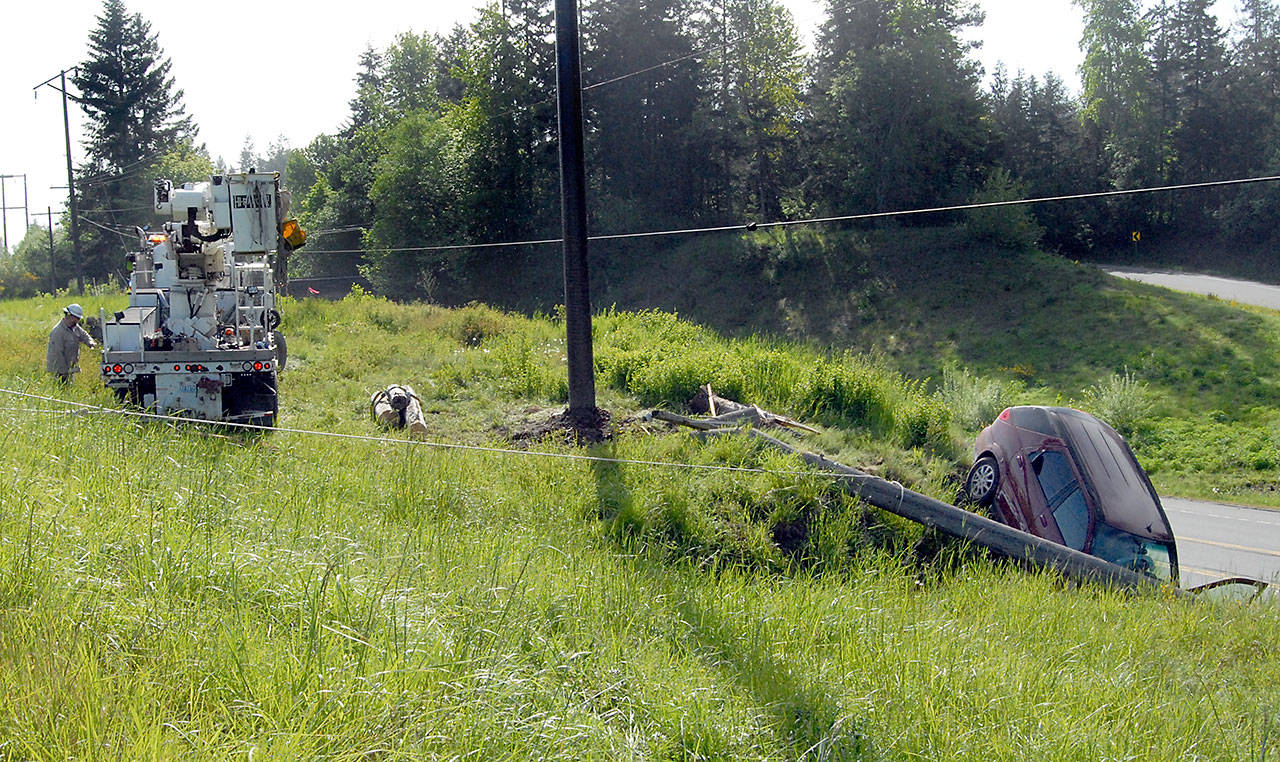 A Clallam County PUD power crew prepares to repair power lines at the top of the Tumwater Truck Route on Wednesday after a car ran off the road and toppled a power pole early Wednesday morning in Port Angeles. (Keith Thorpe/Peninsula Daily News)