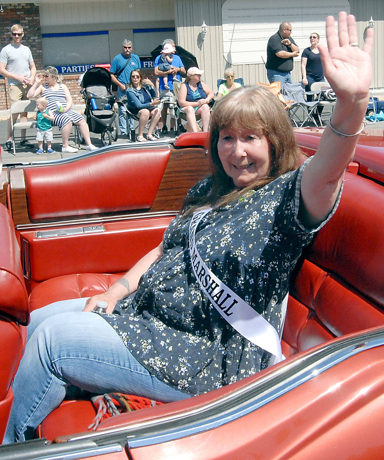 Sequim Irrigation Festival parade Grand Marshal Jaye Moore, retired director of the Northwest Raptor and Wildlife Center, waves to the crowd on Saturday. (Keith Thorpe/Peninsula Daily News)