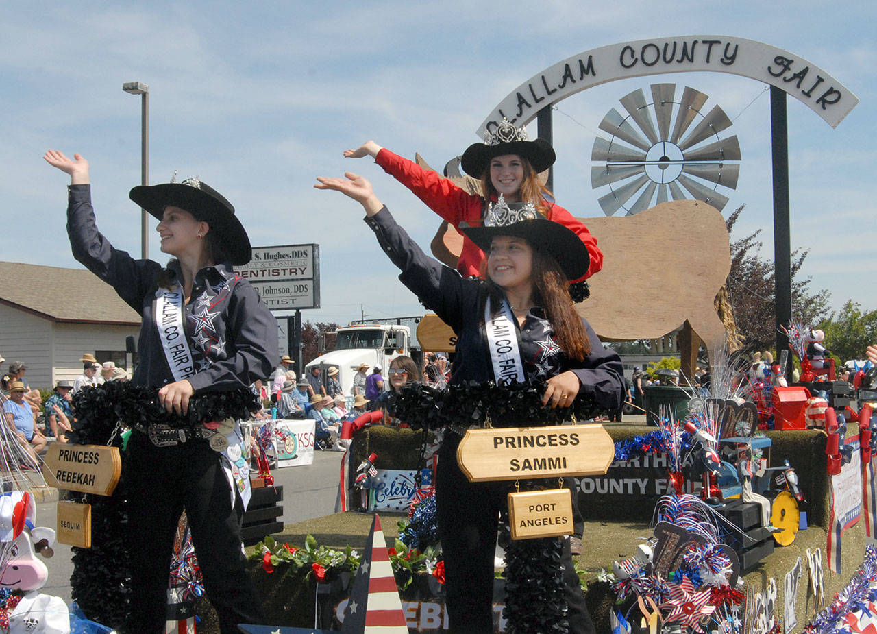 Clallam County Fair Royalty, from left, Princess Rebekah Parker, Queen Saydee Peters and Princess Sammi Bates wave from their fair float on Saturday. (Keith Thorpe/Peninsula Daily News)