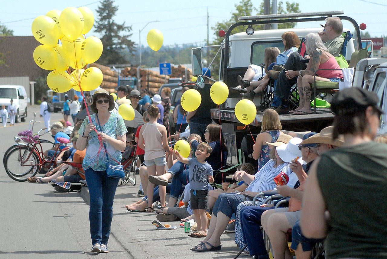 Lori Parkhurst walks the parade route to hand out balloons to young spectators. (Keith Thorpe/Peninsula Daily News)