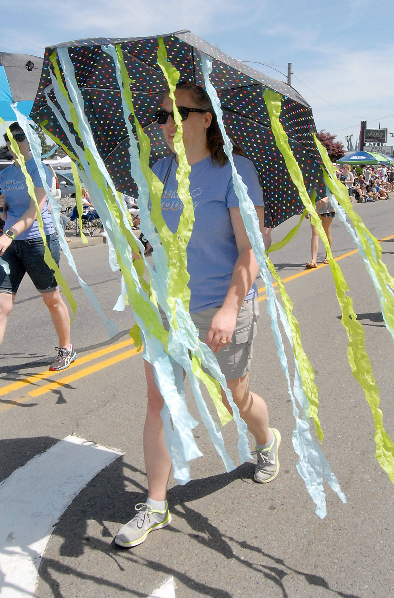 Alicia Disinski marches with an umbrella trailing streamers with a parade entry for Sequim Girl Scouts. (Keith Thorpe/Peninsula Daily News)
