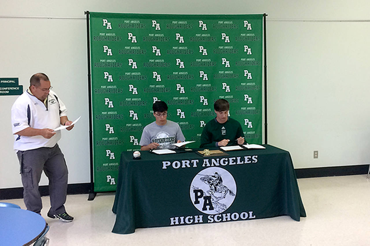 Michael Carman/Peninsula Daily News Port Angeles athletic director Dwayne Johnson, left, looks on as Gavin Guerrero and Seth Scofield sign letters of intent to play baseball for Umpqua Community College in Roseburg, Ore.