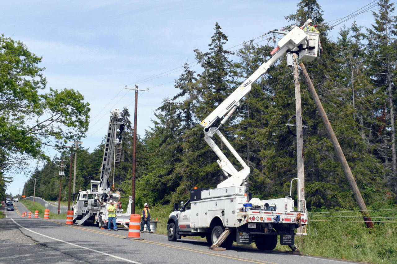 Jefferson County Public Utility District line crews install temporary poles along the north side of Flagler Road on Marrowstone Island on Wednesday in preparation for a new bridge to be built beginning mid-summer. The existing causeway at Kilisut Harbor is a barrier to fish migration and is being opened to allow migration and tidal land restoration. (Jeannie McMacken/Peninsula Daily News)