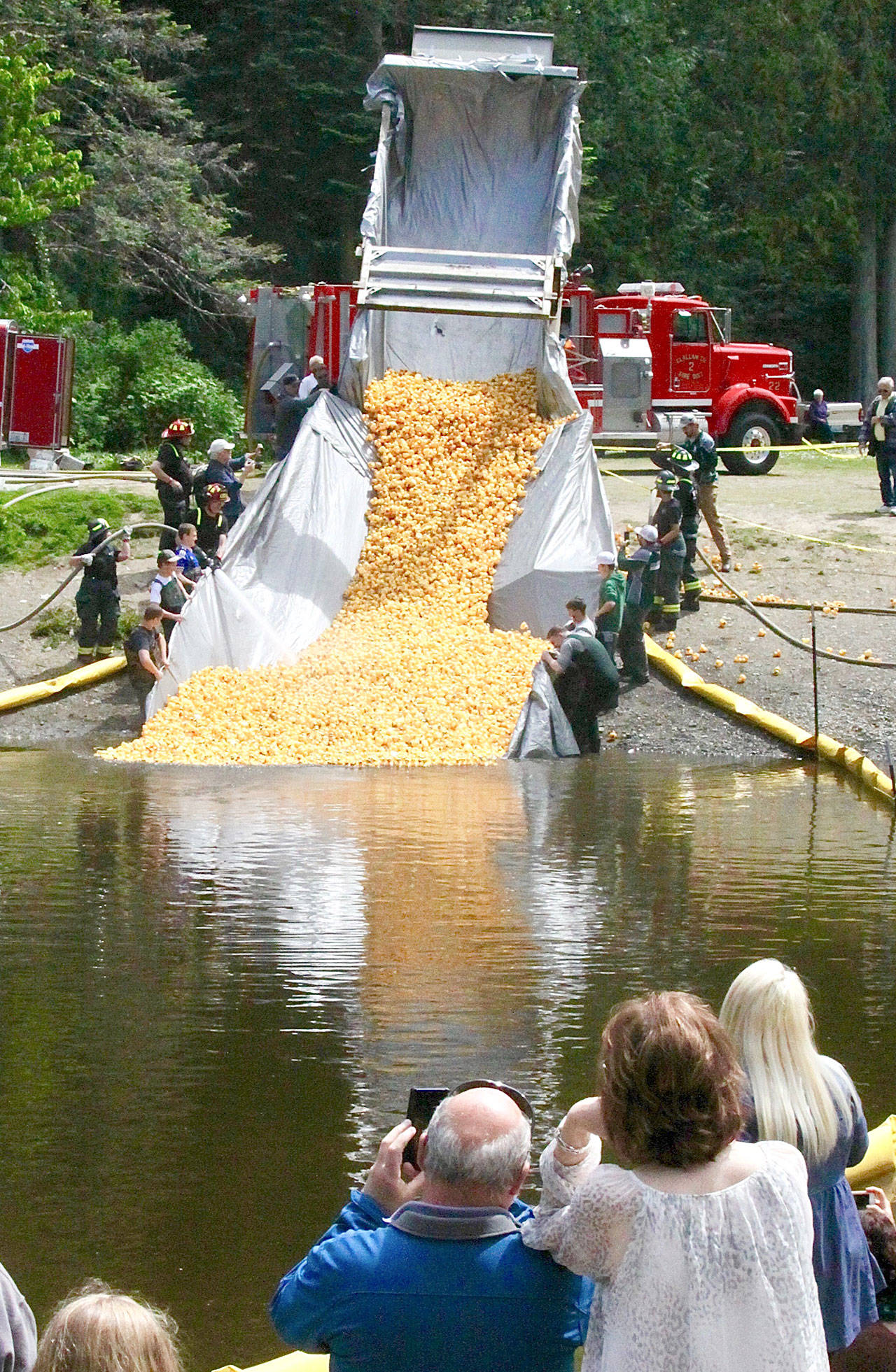 Firefighters blast the 29,159 ducks in this year’s Duck Derby into the Lincoln Park pond Sunday in Port Angeles while contest participants wait. (Dave Logan/for Peninsula Daily News)