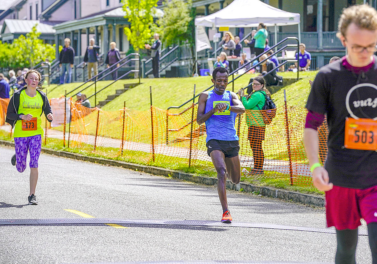 Taye Babeker Tirfea, from Addis Ababa, Ethiopa, stops his watch ase he crosses the line in 37:37 to win the Men’s Elite 2019 Rhody Run at Fort Worden State Park on Sunday. (Steve Mullensky/for Peninsula Daily News)
