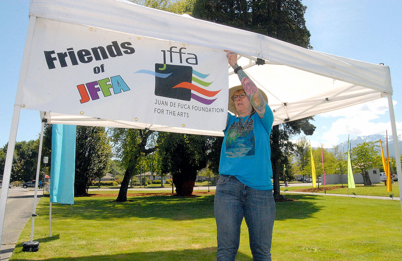 Festival volunteer Jeanette Painter attaches a banner to a welcome tent on the grounds of Vern Burton Community Center in Port Angeles on Thursday in preparation for this weekend’s Juan de Fuca Festival of the Arts, which begins today. (Keith Thorpe/Peninsula Daily News)
