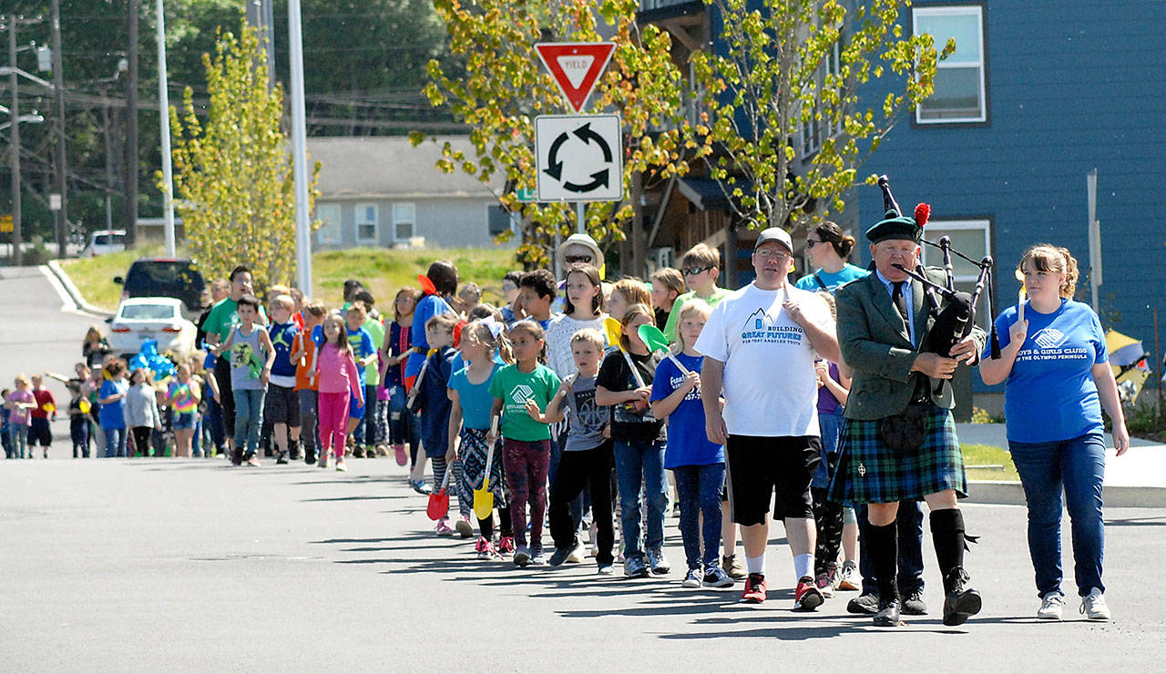 Bagpiper Thomas McCurdy leads a procession of adults and children armed with shovels from the Mount Angeles Unit of the Boys & Girls Clubs of the Olympic Peninsula to a groundbreaking Friday at the site of their future club at Lauridsen Boulevard and Francis Street in Port Angeles. (Keith Thorpe/Peninsula Daily News)