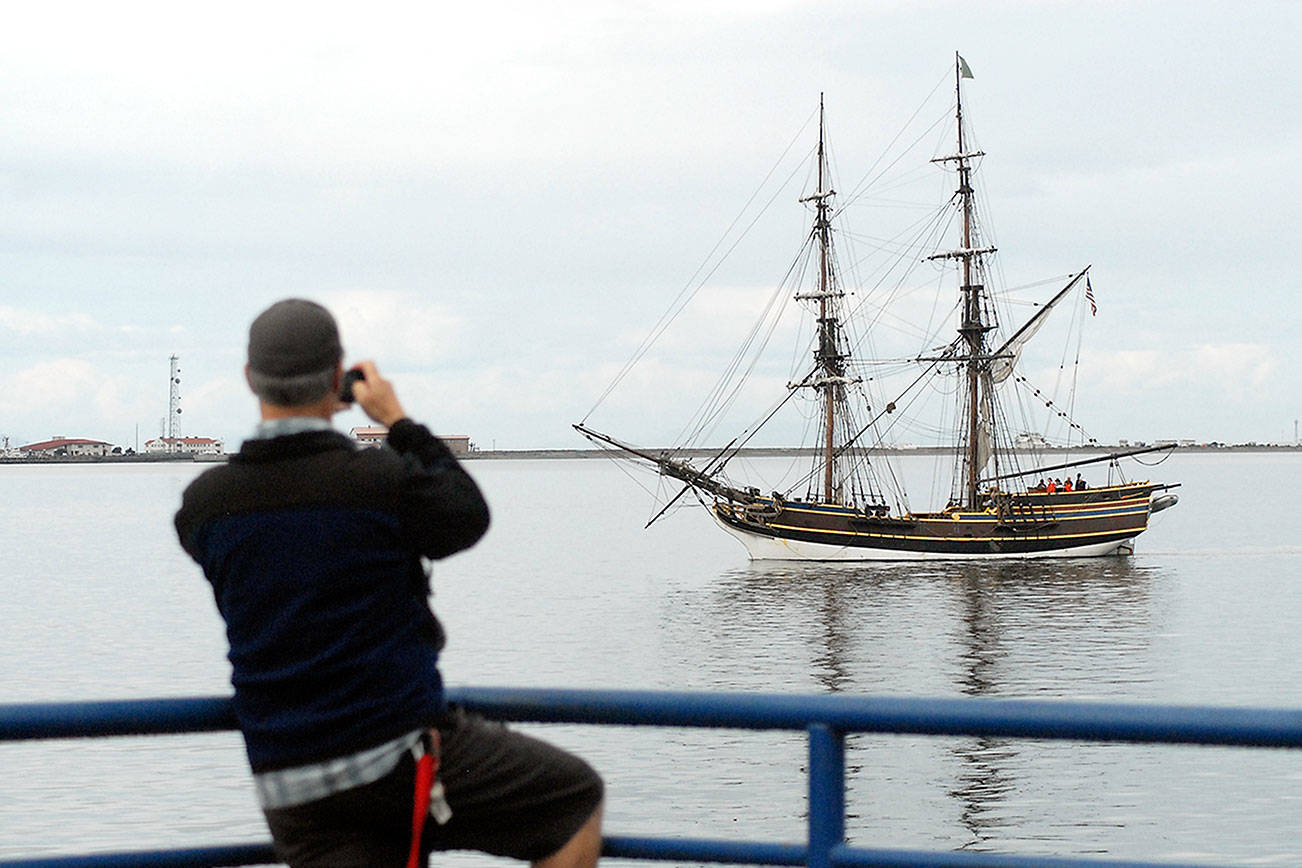 Keith Thorpe/Peninsula Daily News Christopher Thomsen of Port Angeles takes a cellphone photo of the tallship Lady Washington as it does a beauty pass of City Pier after arriving in Port Angeles on Thursday.