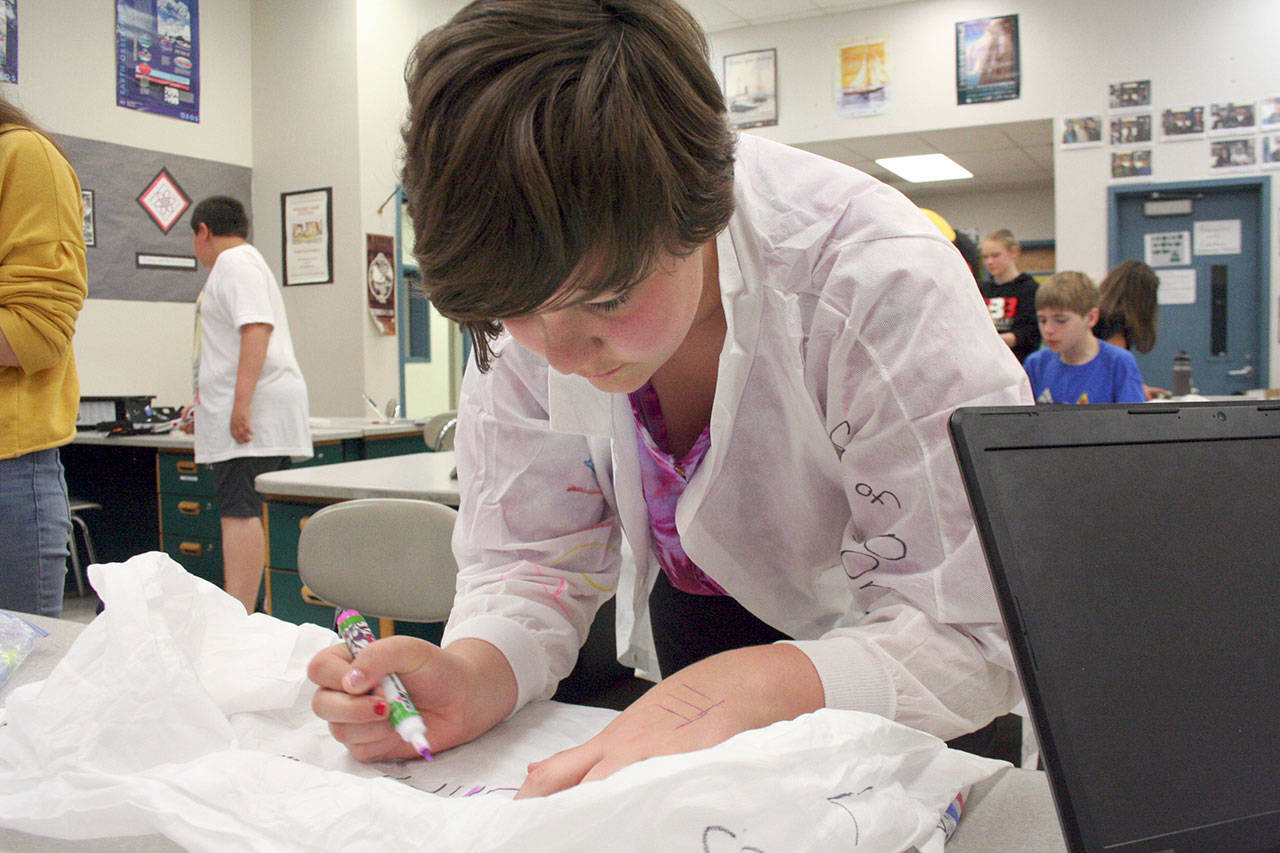 Rowan Santerre, a sixth-grader at Blue Heron Middle School in Port Townsend, decorates her team’s lab coats as part of the NASA Challenge. (Brian McLean/Peninsula Daily News)