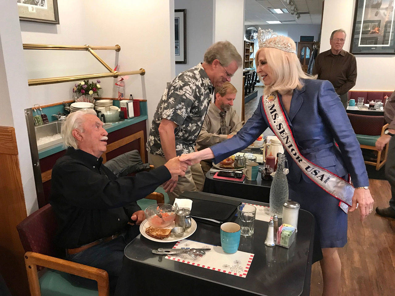 Newly named Ms. Senior USA Cherie Kidd of Port Angeles, a member of the Port Angeles Business Association, greets incumbent Clallam Fire District 2 Commissioner Richard Ruud and primary election challengers Steve Hopf, center, and Keith Cortner, right, at a PABA voter forum Tuesday. (Paul Gottlieb/Peninsula Daily News)