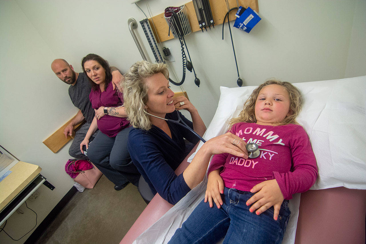 Dr. Jessica Colwell examines Azila Black, 3, as her parents Ryan and Amber Black look on at North Olympic Healthcare Network. (Jesse Major/Peninsula Daily News)
