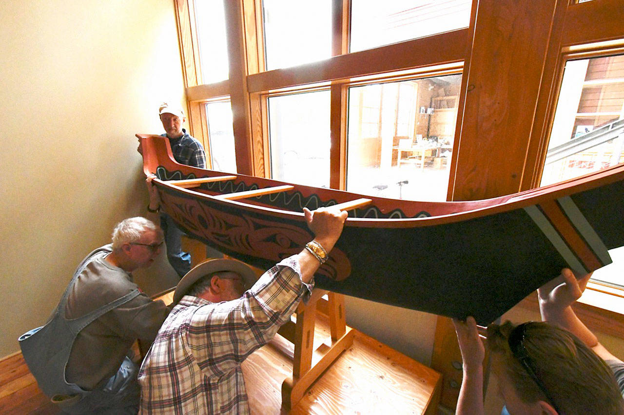 A replica of a dugout Salish Coast canoe carved and decorated by Dale Faulstich, top left, and Andy Pitts, lower right, was installed in the Northwest Maritime Center’s Wooden Boat Chandlery as part of the Chetzemoka Trail project. The man between them is unidentified. The eagles depicted on the side represent two young eaglets without feathers or developed wings that had fallen out of their nest near Pitts’ studio in Sequim. They suffered no harm after the more than 100-foot fall and were placed back in the nest where they remain. The two artists felt it was an appropriate to name the canoe “Two Eagles.” (Jeannie McMacken/Peninsula Daily News)