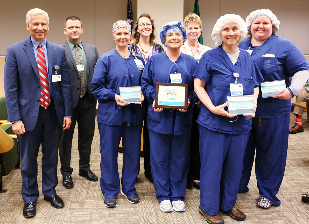 From left, are Olympic Medical Center CEO Eric Lewis, OMC Board President John Nutter, OMC Surgical Services Supervisor Sarah Winfield and Chief Nursing Officer Lorraine Wall with operating room nurses, in scrubs, DeAnn Pype, Joellyn Jensen, Ellen Adams and Heidi Mattern.