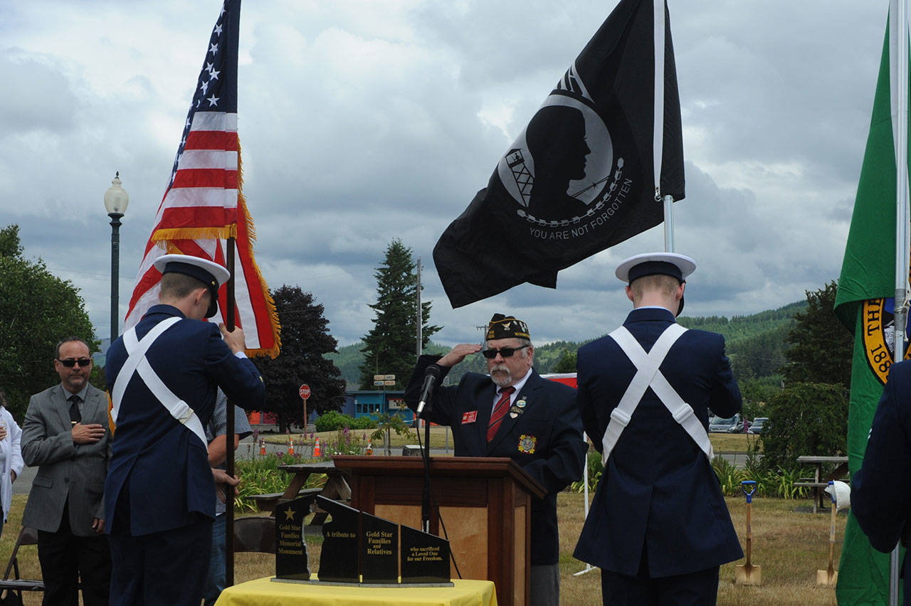 The U.S. Coast Guard Quillayute posts the colors while VFW Post 9106 Cmdr. Tom Hughes of Forks salutes during the groundbreaking ceremony for the Gold Star Families Monument at the Forks Transit Center. (Lonnie Archibald/for Peninsula Daily News)