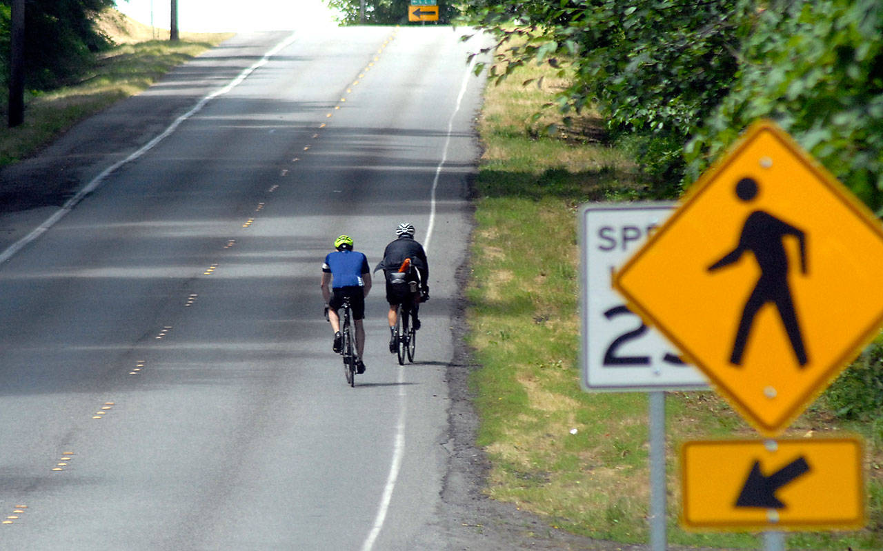 A pair of bicyclists make their way up the steep incline of Hill Street in Port Angeles on Wednesday. A portion of Olympic Discovery Trail will be built north of the street under a $1.4 million state grant announced this week. (Keith Thorpe/Peninsula Daily News)