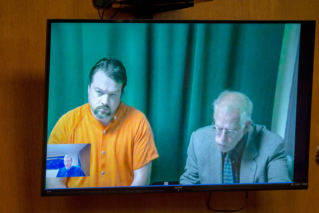 Matthew Wetherington, left, appears on video in Clallam County Superior Court on Monday. Wetherington, accused of killing his wife and her three children, was ordered held in the Clallam County jail on $5 million bail. (Jesse Major/Peninsula Daily News)