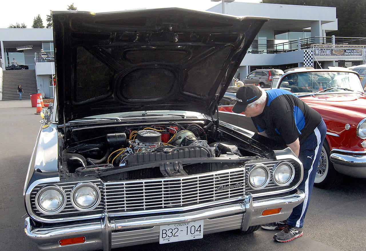 Bob Larsen of Port Angeles looks under the hood of a 1964 Chevy 409 on Friday evening at the 22nd annual Ruddell Cruise-In at Ruddell Auto Plaza in Port Angeles. (Keith Thorpe/Peninsula Daily News)