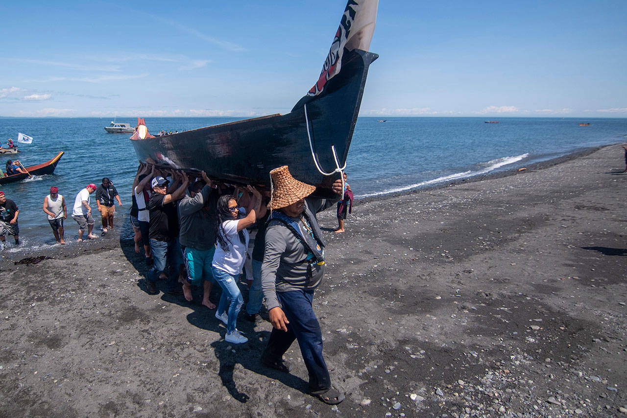 A canoe is carried onto the beach on the Lower Elwha Klallam Tribe’s reservation during the Paddle to Lummi on Sunday. (Jesse Major/Peninsula Daily News)