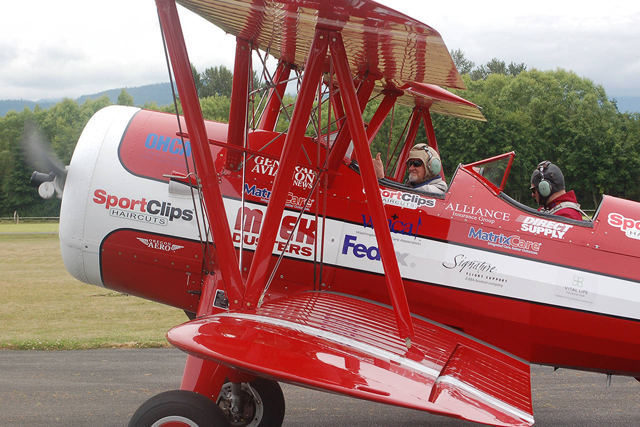 Clint Cawley of the Ageless Aviation Dreams Foundation taxis the “Red Stearman” biplane in at the Sequim Valley Airport as retired Air Force veteran Ken Leuthold gives an emphatic thumbs-up. (Conor Dowley/Olympic Peninsula News Group)