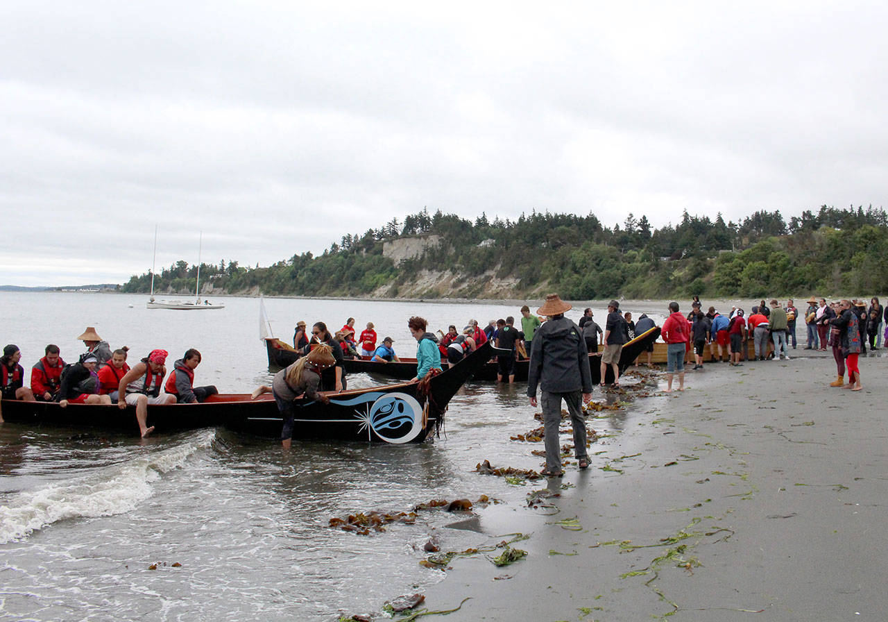 Three canoes arrive on shore in Port Townsend and are carried up the beach by fellow tribe members, volunteers and Port Townsend High School athletes. (Zach Jablonski/Penninsula Daily News)                                Three canoes arrived on shore in Port Townsend and were carried up the beach by fellow tribe members, volunteers and Port Townsend High School athletes. (Zach Jablonski/Penninsula Daily News)