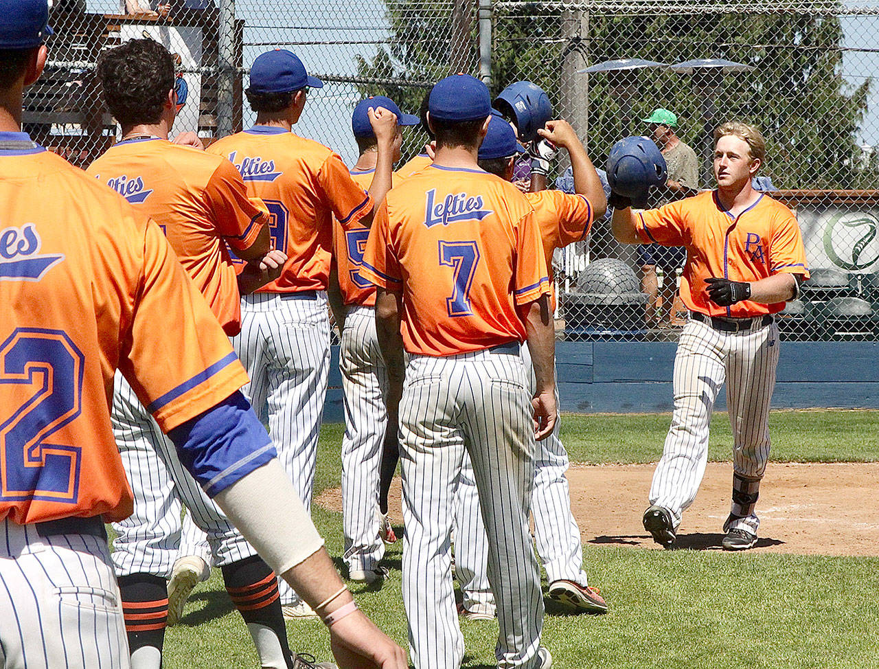 The Lefties’ Evan Hurn, at right, of Sequim, receives congratulations from his teammates after hitting a home run in Port Angeles’ 8-6 win Sunday over Kelowna at Civic Field. (Dave Logan/for Peninsula Daily News)