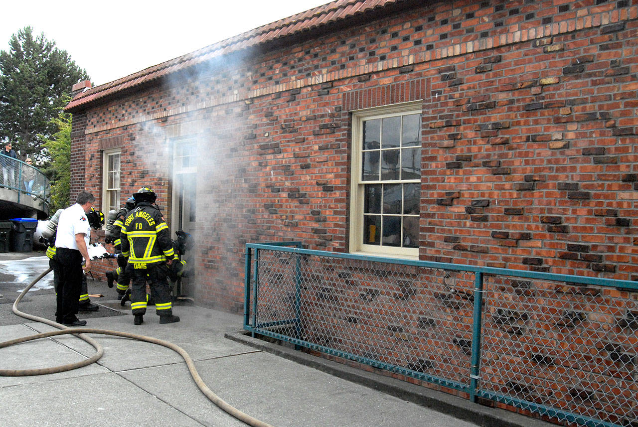 Smoke is seen coming from the back of the Port Angeles Visitor Center at 121 E. Railroad Ave. on Tuesday after small flames were found shooting up through the floor near a back door to the structure. (Keith Thorpe/Peninsula Daily News)