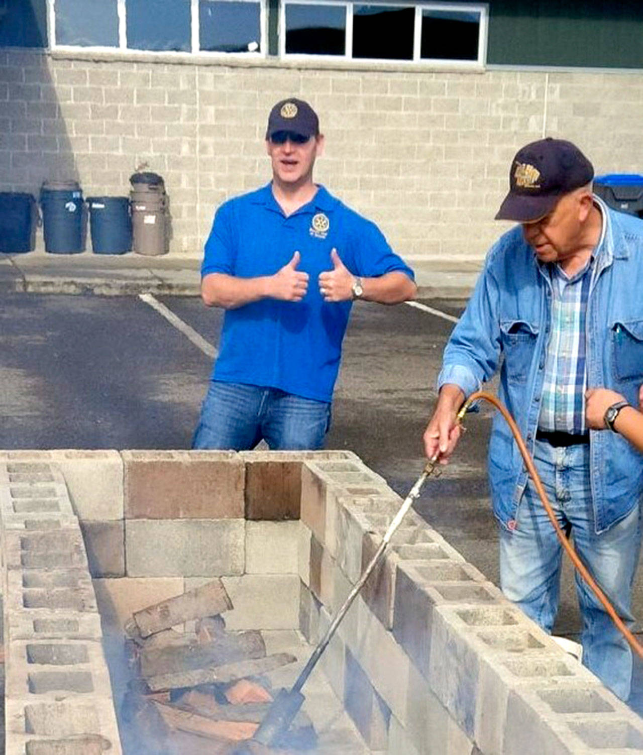 Ed Ebling and Lang Hadley ready a fire for the Rotary Club of Sequim’s annual Salmon Bake. The event returns from noon to 4 p.m. Aug. 11.