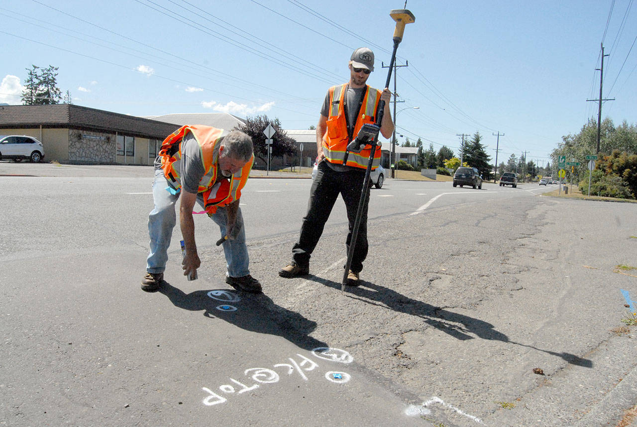 Scot Clark, left, and Trey Hoover of Sequim-based Clark Land Office locate and mark the location of a future wheelchair ramp at the corner of East 13th Street and Lauridsen Boulevard in preparation for improvements to Lauridsen scheduled to begin Monday. (Keith Thorpe/Peninsula Daily News)