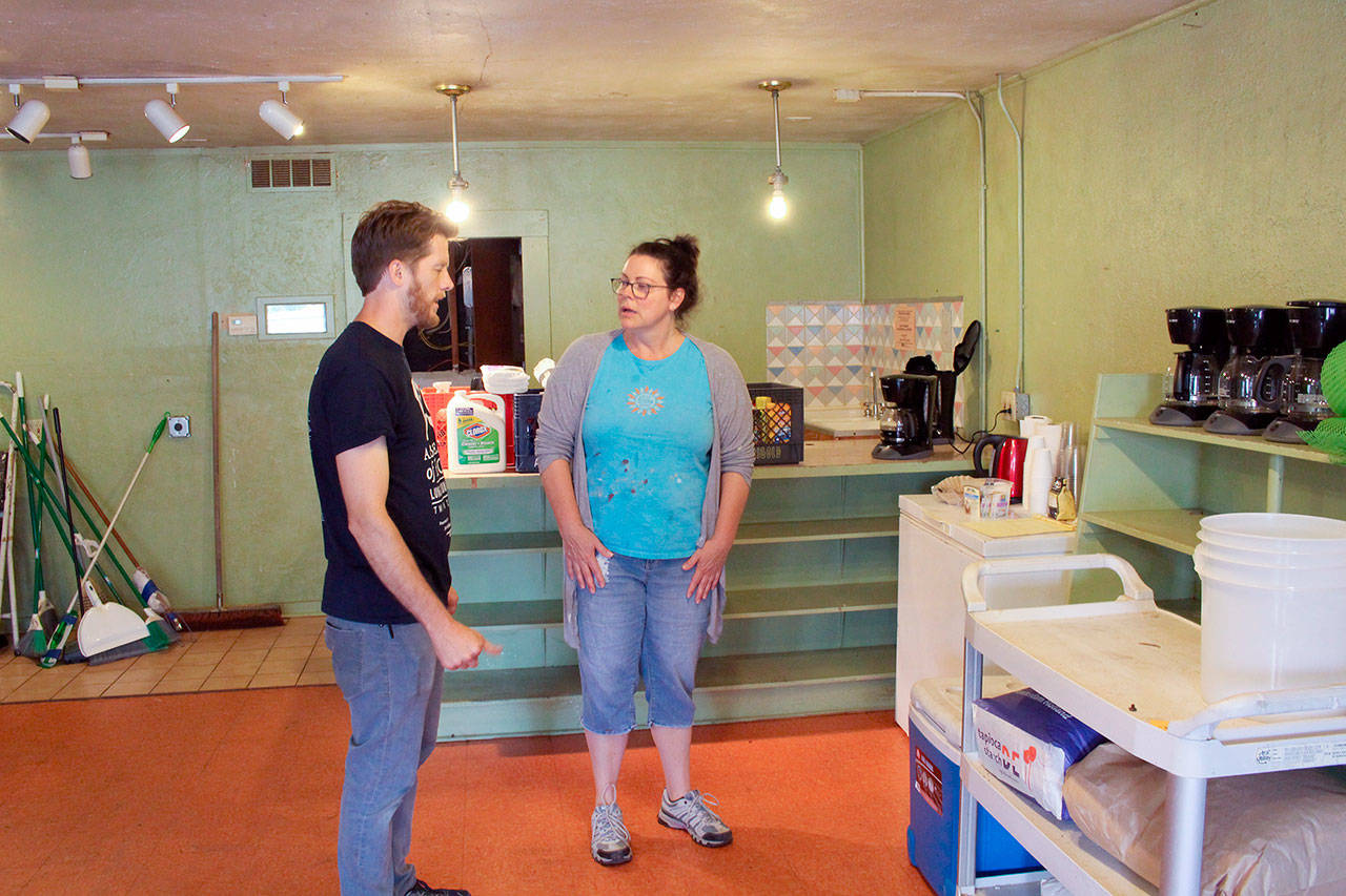 Recovery Cafe Coordinator Brian Richardson speaks with Maura Walsch on Friday, as they work on cleaning the location of the Dove House Recovery Cafe. (Zach Jablonski/Peninsula Daily News)