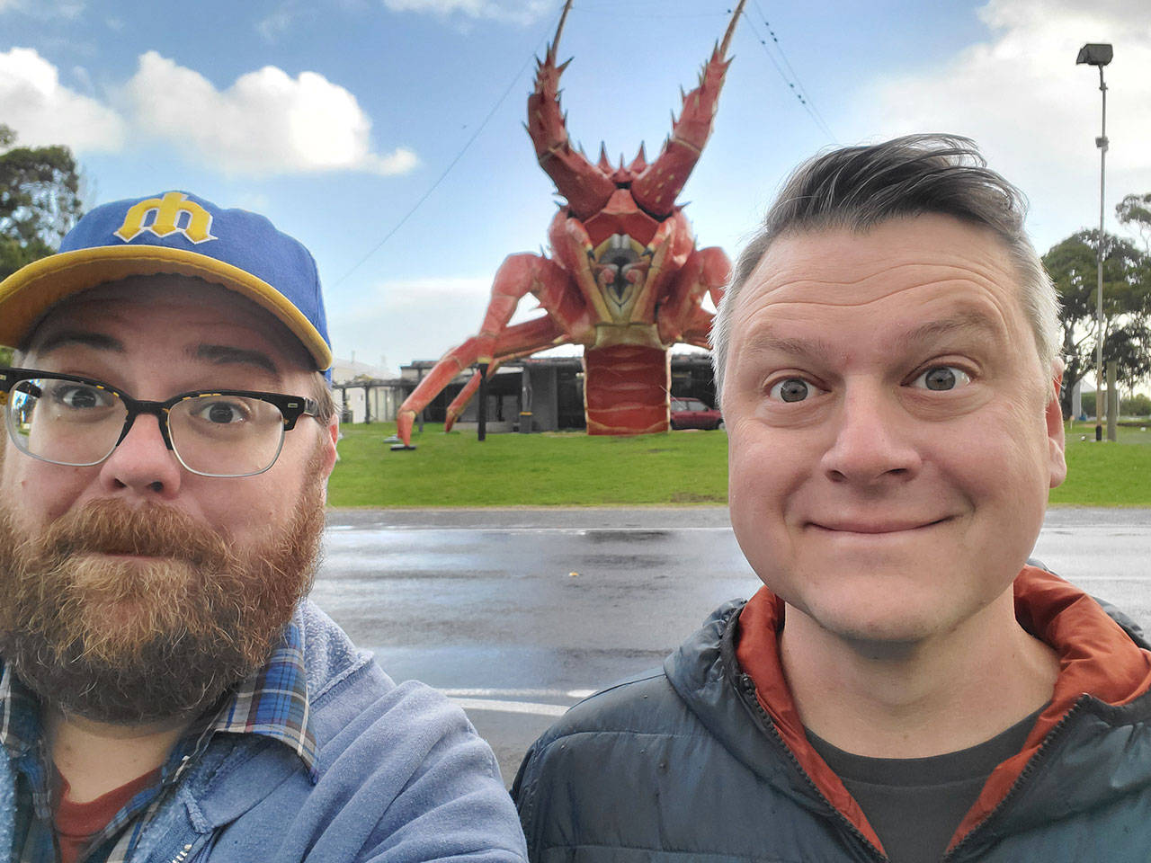 Andrew Walsh, left, and Luke Burbank, hosts of the podcast “Too Beautiful to Live,” visit “Larry the Lobster” in Kingston SE, Australia, during one of their latest adventures. The podcast is nearing its 3,000th episode and will be featured live during Thing at Fort Worden on Aug. 24 at the Wheeler Theater, where Walsh got married. (American Public Media)