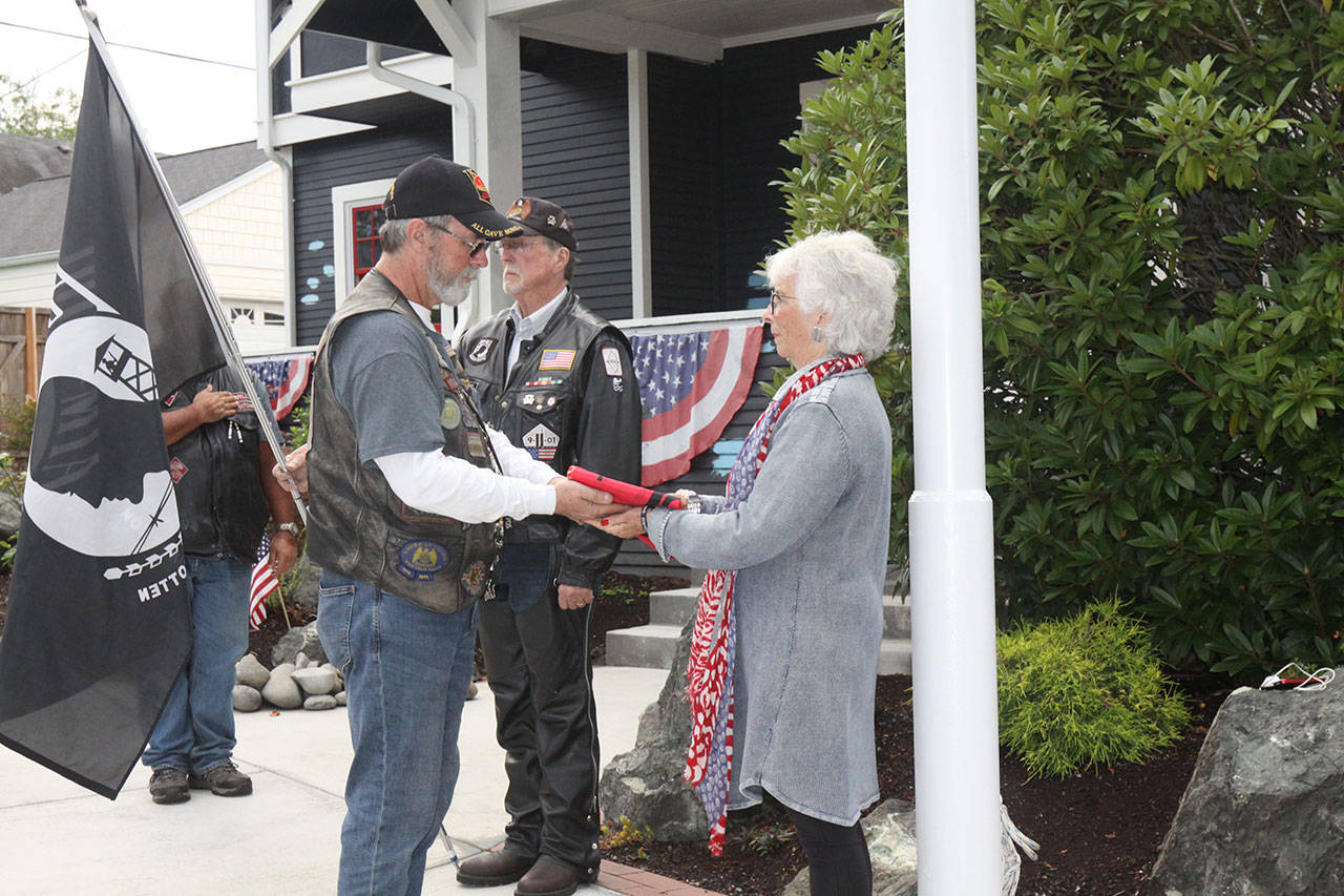 Hy “Crash” Libby presents a KIA flag to Betsy Reed Schultz on Saturday during a ceremony honoring her and her late son, Army Special Operations Capt. Joseph Schultz, at the Captain Joseph House in Port Angeles. (Dave Logan/for Peninsula Daily News)