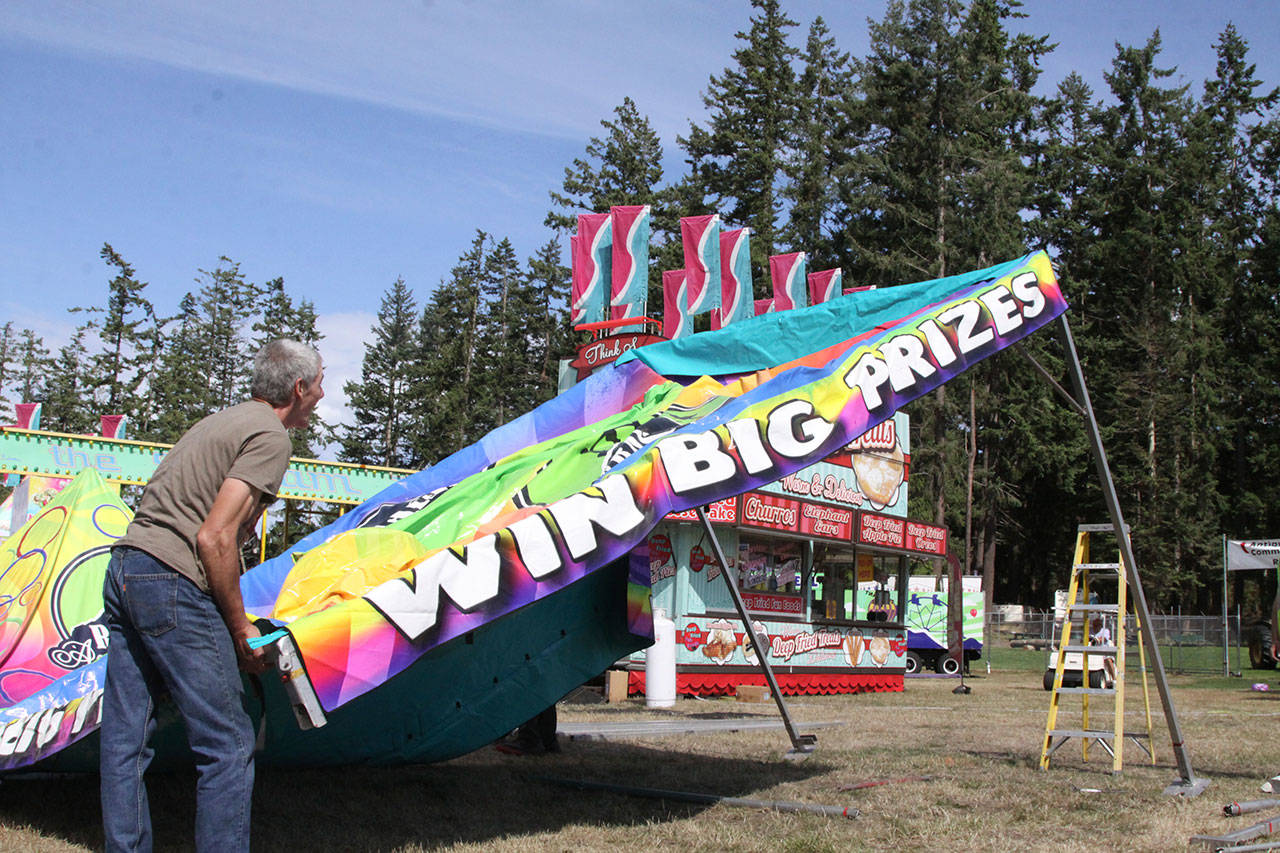 Kevin Johnson of Rainier Amusement Co. lifts up a tent as part of the midway attractions at the Clallam County Fair in Port Angeles, which starts Thursday. (Dave Logan/for Peninsula Daily News)