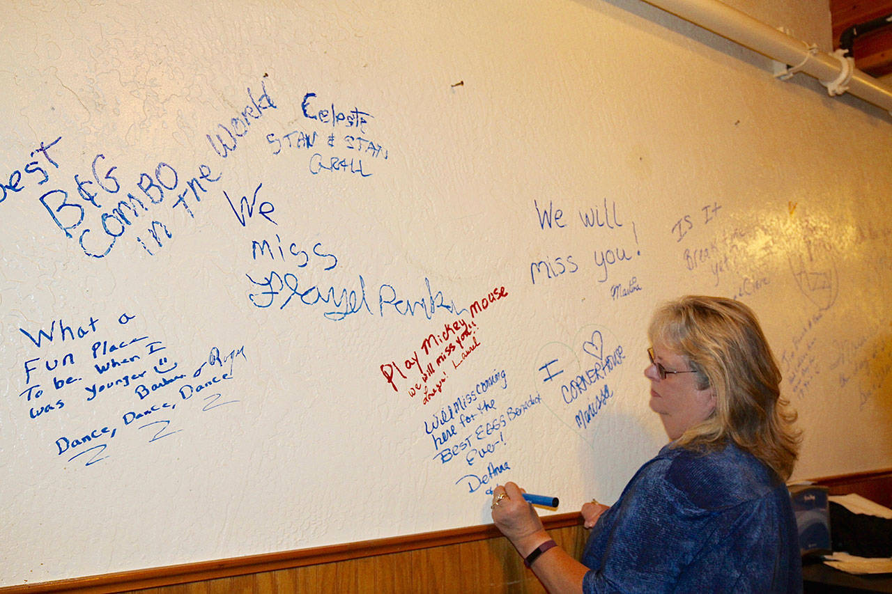 DeAnna Stossel, a long-time customer at the Cornerhouse Restaurant, writes a farewell message on the walls in the bar area of the eatery at its closing party. (Dave Logan/for Peninsula Daily News)