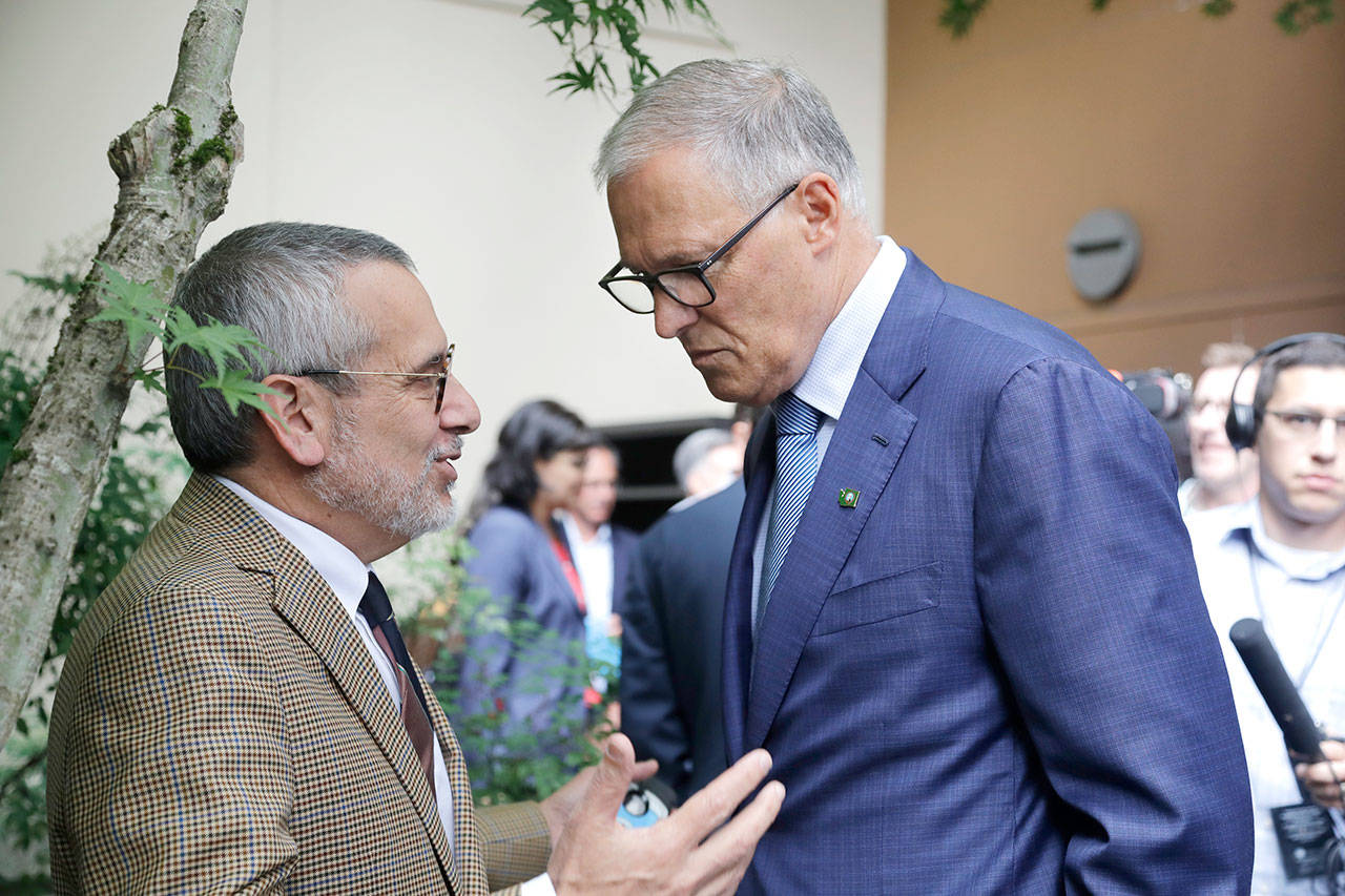 Gov. Jay Inslee, right, speaks with David Postman, his chief of staff, before talking with reporters about his plans to run for a third term as governor Thursday. (AP Photo/Elaine Thompson)