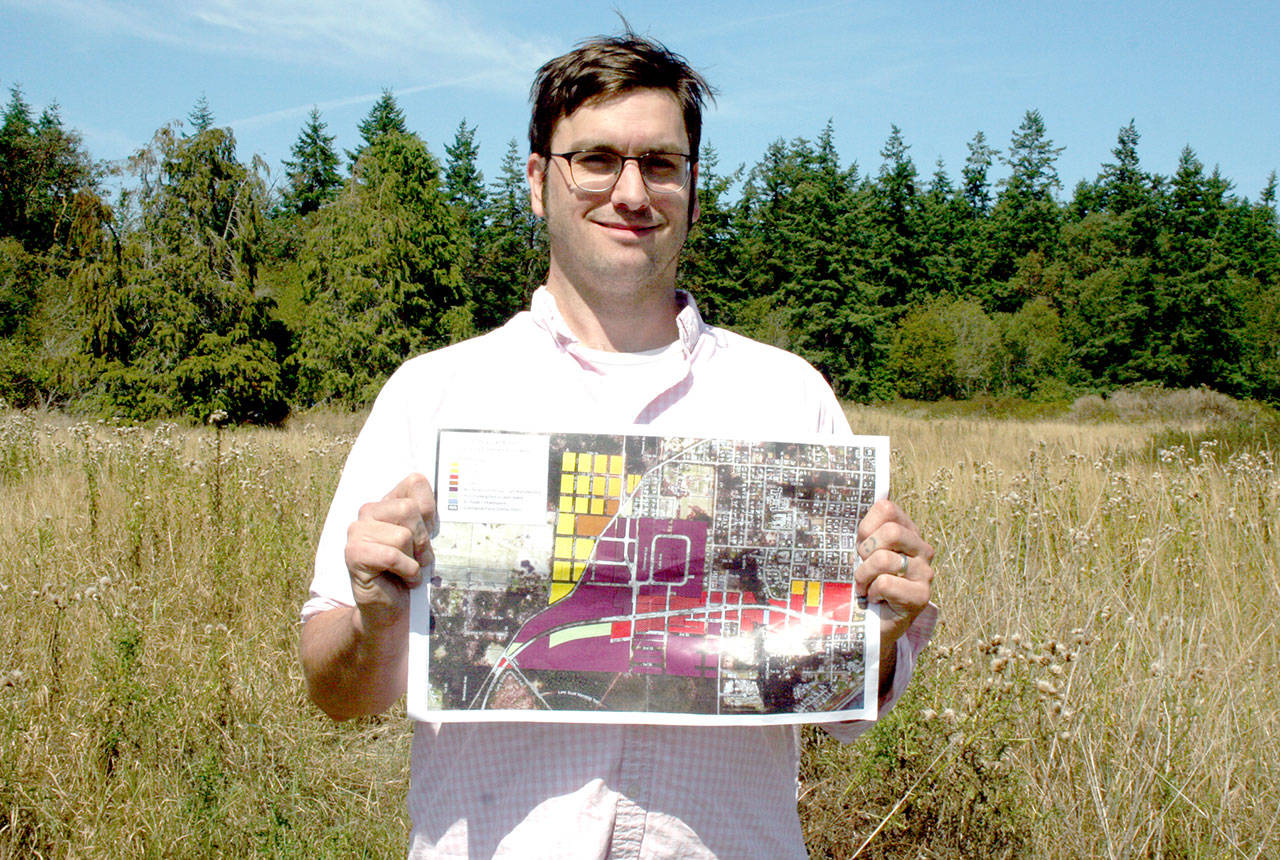Paul Rice, the chair of the Port Townsend Planning Commission, displays the subarea map for Rainier Street and Upper Sims Way. Behind him is a lot at the corner of Rainier and Sevenths streets where the Mt. Townsend Creamery plans to relocate and become a cornerstone of the new development area. (Brian McLean/Peninsula Daily News)
