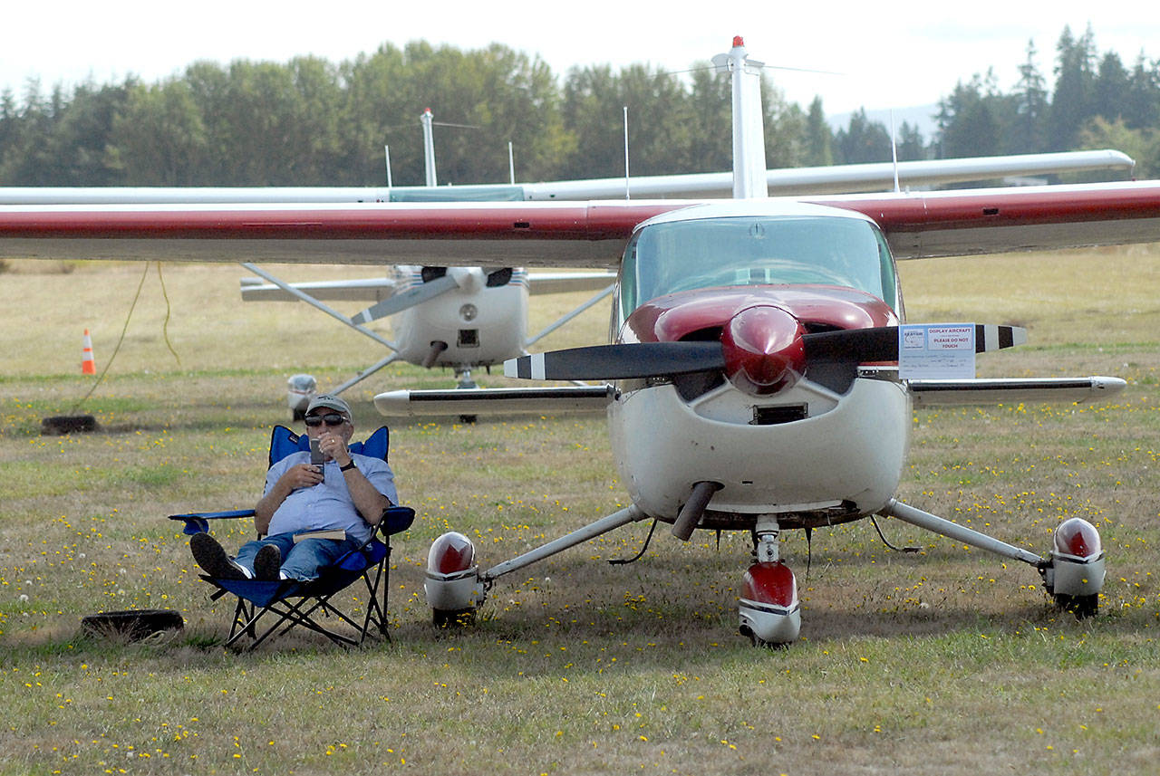 Jay Palmer of Diamond Point sits in the shade generated by the wing of his 1960 Cessna Cardinal during Saturday’s Air Affaire. (Keith Thorpe/Peninsula Daily News)