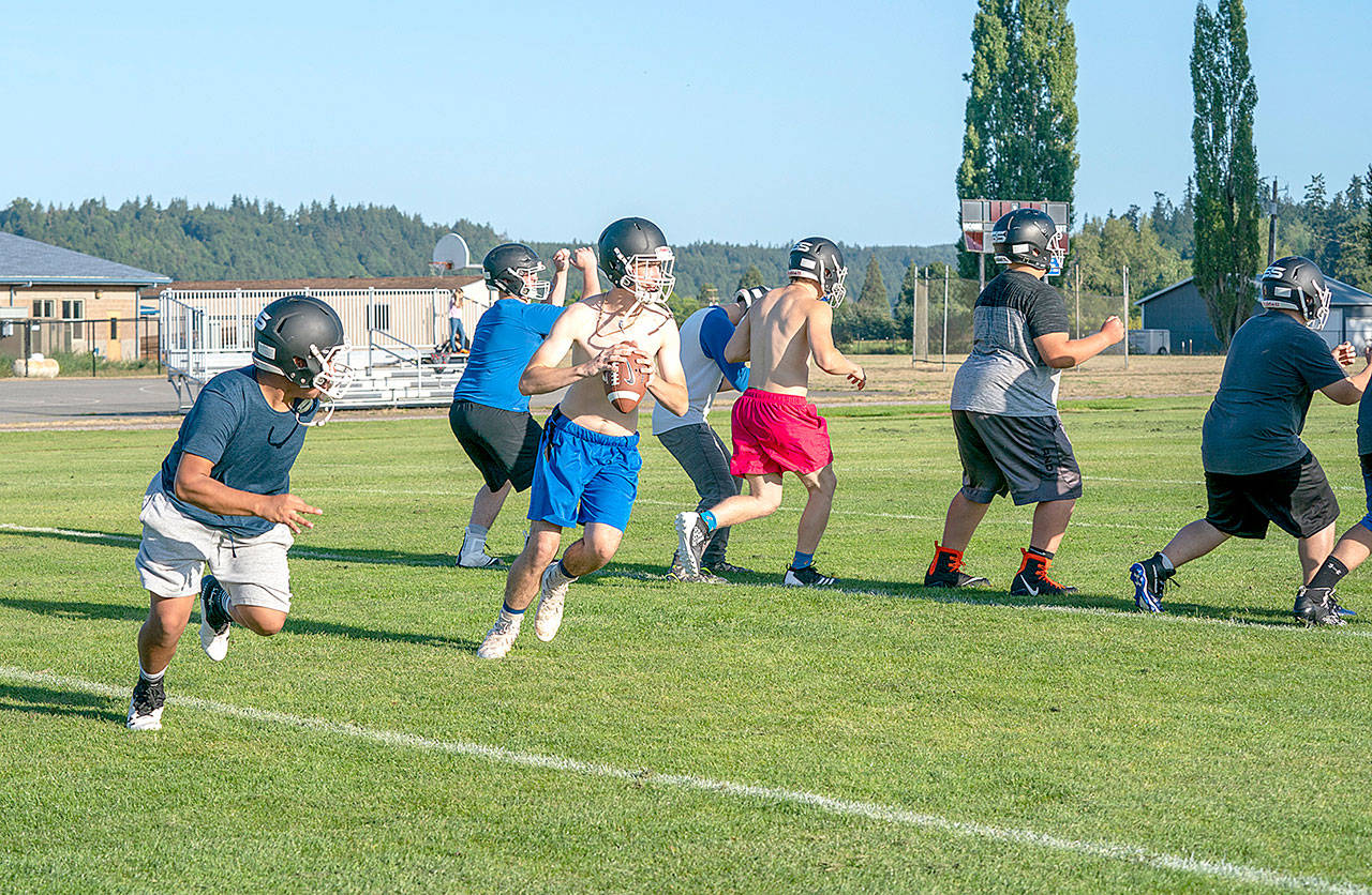 Steve Mullensky/for Peninsula Daily News Wyatt Pennington looks for a receiver downfield during Cowboy practice on Thursday in Chimacum. The Cowboys have lots of size on their line and plenty of speed and are looking to improve their defense this year.