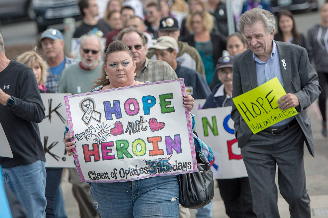 Miranda Beck of Port Angeles holds a sign as the International Overdose Awareness Day walk makes its way toward the Port Angeles City Pier in 2018. (Jesse Major/Peninsula Daily News)