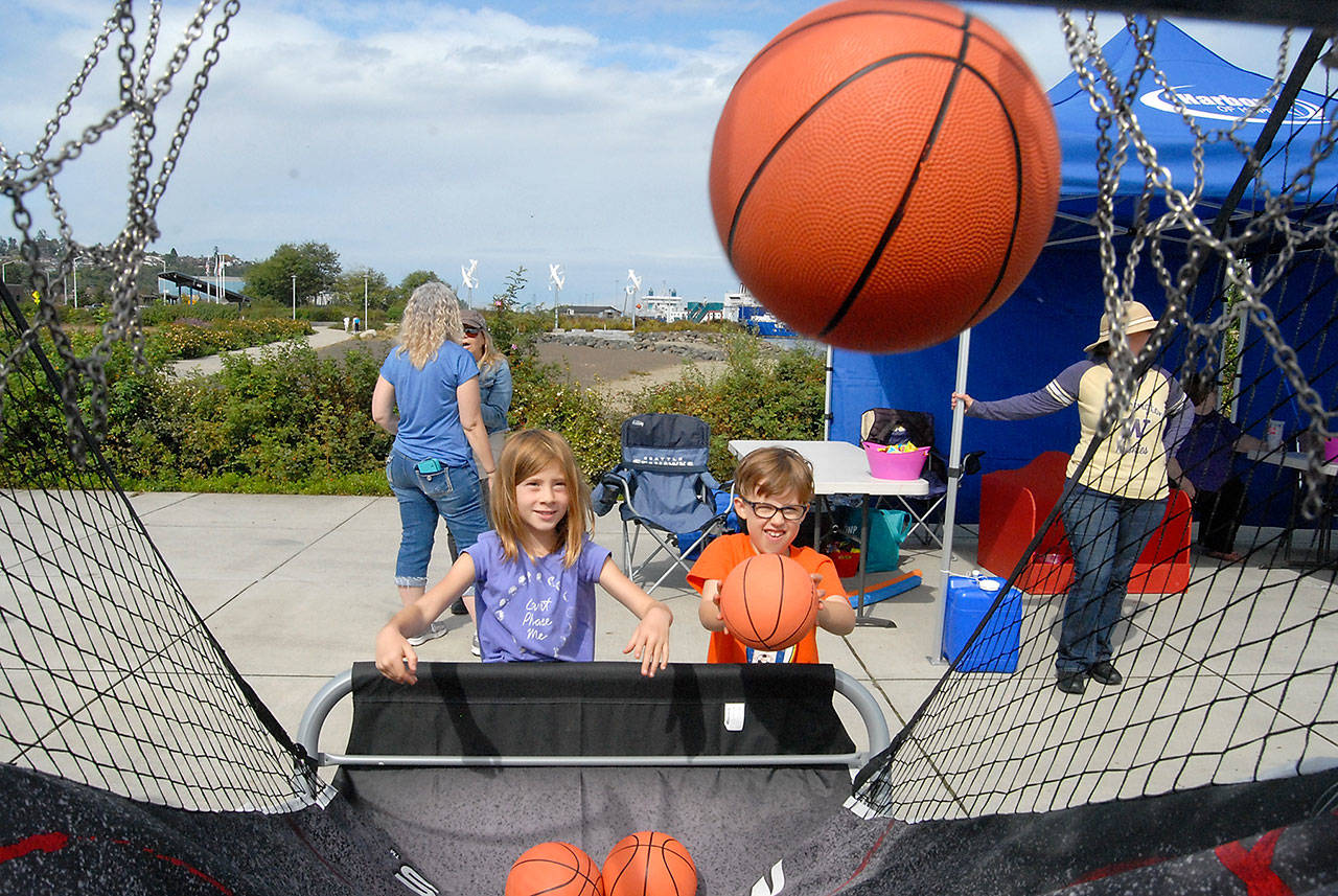 From left, cousins Ivy Bishop, 7, of Bellingham and Maeve Caron, 6, of Portland, Ore., toss basketballs during a hoops game set up at Pebble Beach Park in Port Angeles during Saturdays Jammin in the Park. (Keith Thorpe/Peninsula Daily News)
