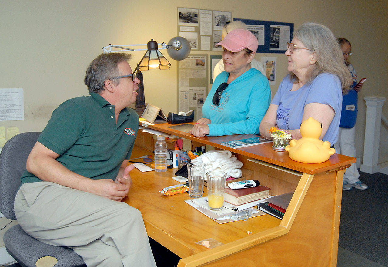 Tim Chamberlain, former manager of the Downtown Hotel in Port Angeles, left, speaks with sisters Margaret Carr of Port Angeles and Trish Holden of Sequim, right, at the hotel’s front desk during final open house Tuesday. (Keith Thorpe/Peninsula Daily News)