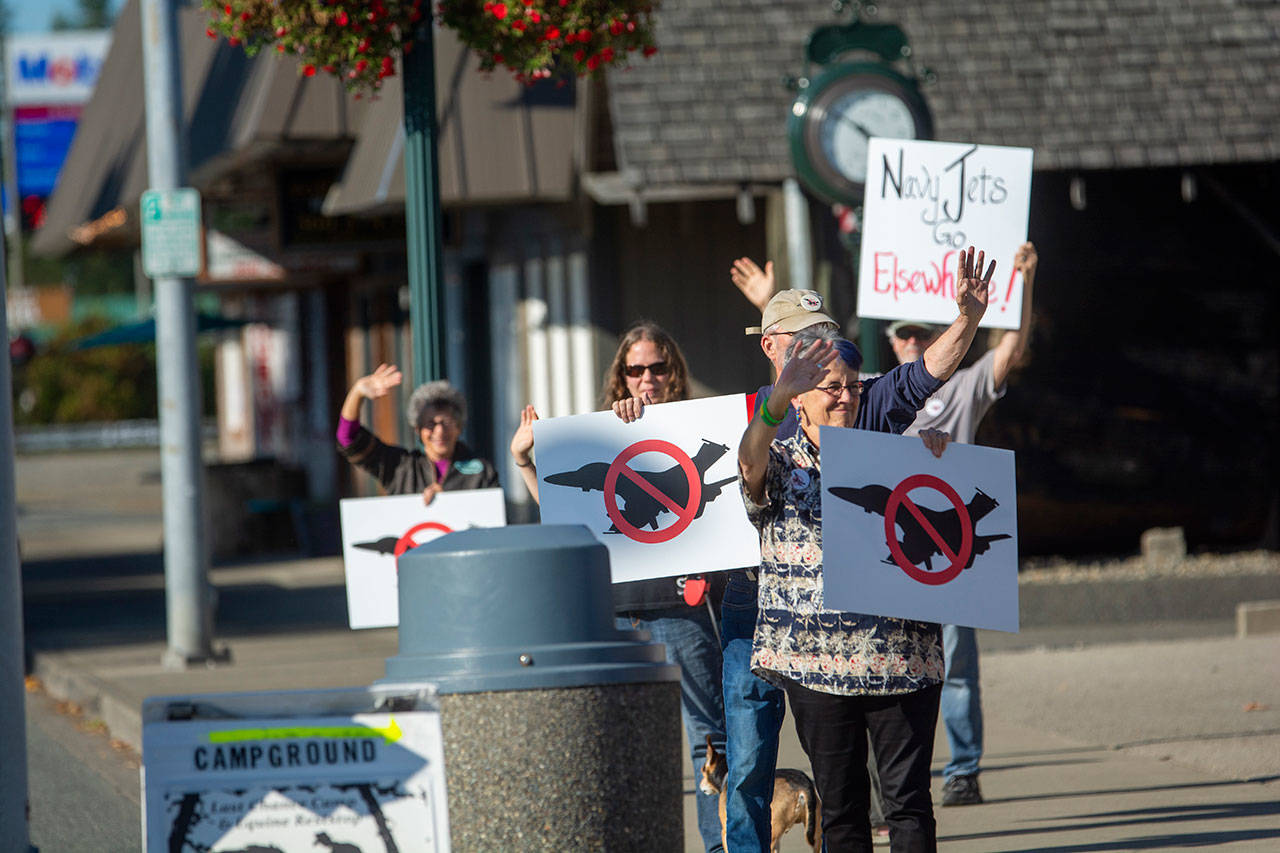Protesters who oppose FA-18 Growler jets from Naval Air Station Whidbey Island stand outside the Rainforest Arts Center in Forks before U.S. Rep. Derek Kilmer’s town hall Wednesday evening. (Jesse Major/Peninsula Daily News)