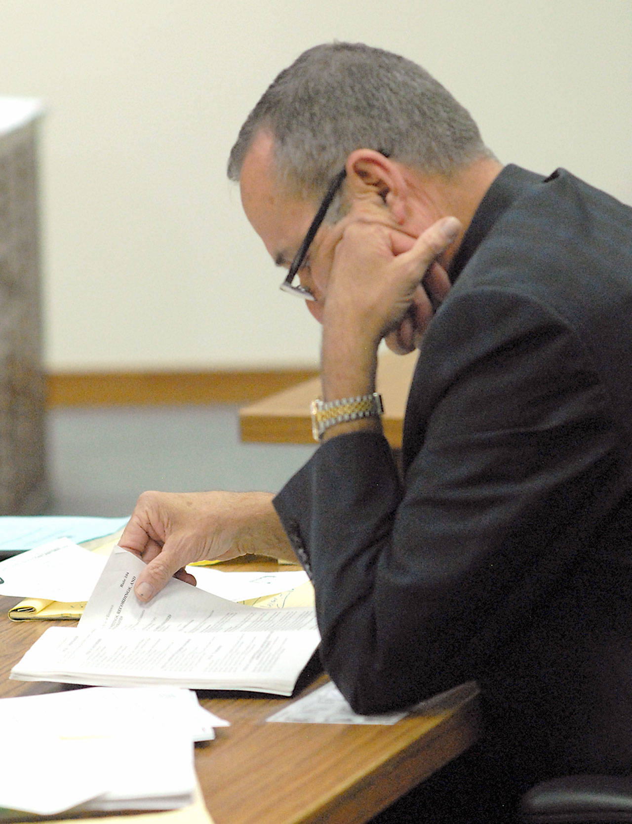 William Payne, attorney for Olympic Medical Center Commissioner District 1 candidate Ann Marie Henninger, examines court papers during Henninger’s hearing on Thursday contesting her eligibility for the seat. (Keith Thorpe/Peninsula Daily News)
