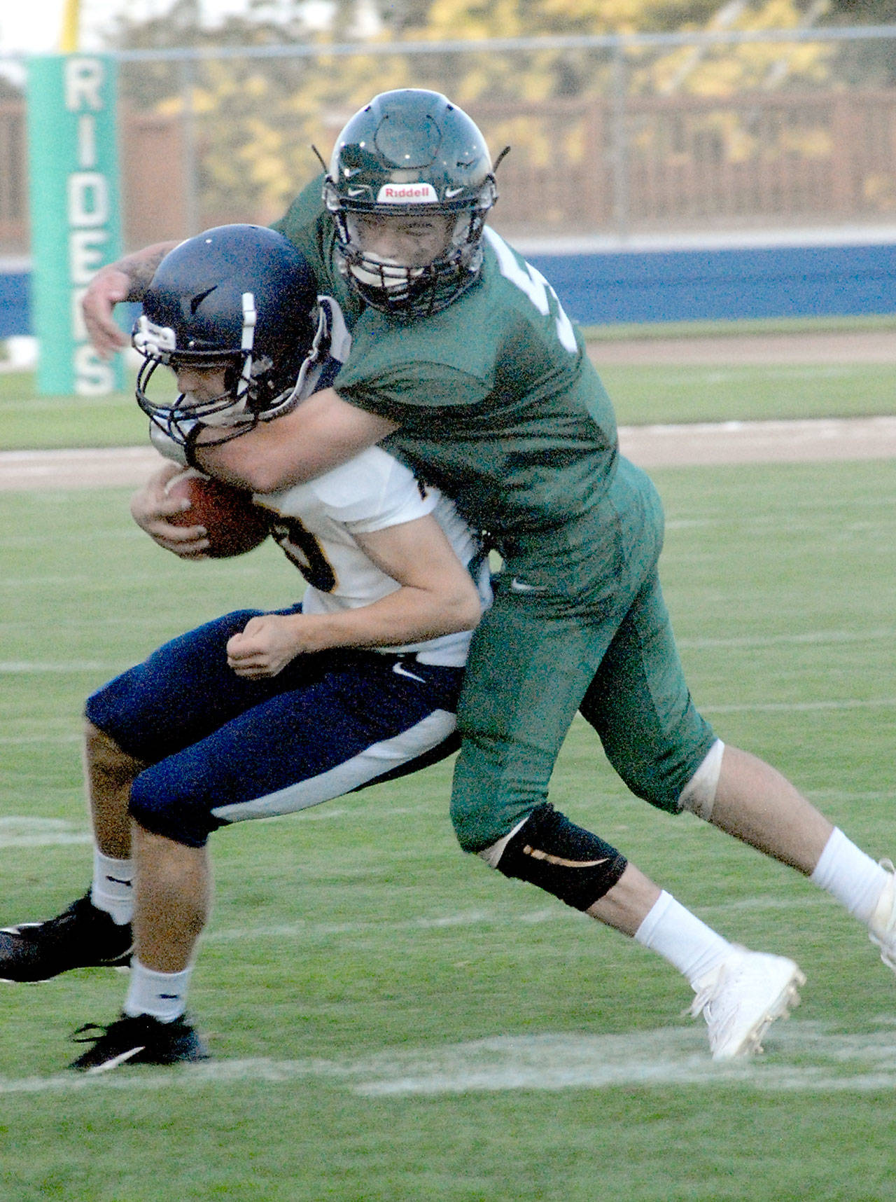 Keith Thorpe/Peninsula Daily News Forks’ wide receiver Logan Olson is wrapped up by Port Angeles’ Tyler Bowen during the first quarter on Friday night.