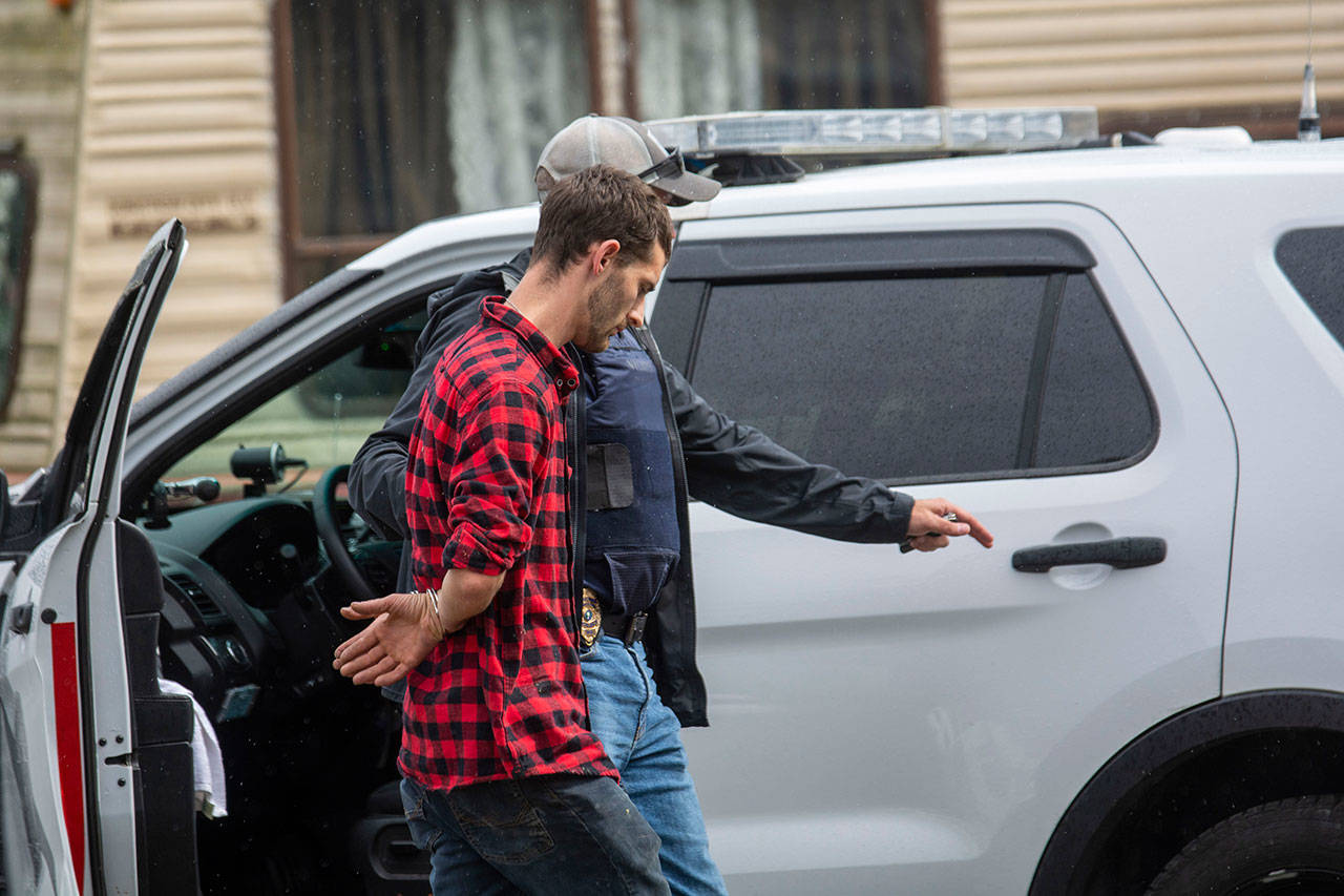 Alex Frost, who was charged Monday with possession of a stolen vehicle and second-degree possession of stolen property, is escorted to the back of a State Patrol vehicle Thursday. (Jesse Major/Peninsula Daily News)