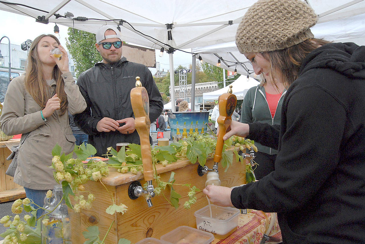 Katie Mountifield, an employee of Port Townsend Brewing, right, pours a sample of her company’s beer for Christina and Cody Pettersen of Seattle during the 2018 Arts & Draughts Festival. (Keith Thorpe/Peninsula Daily News)