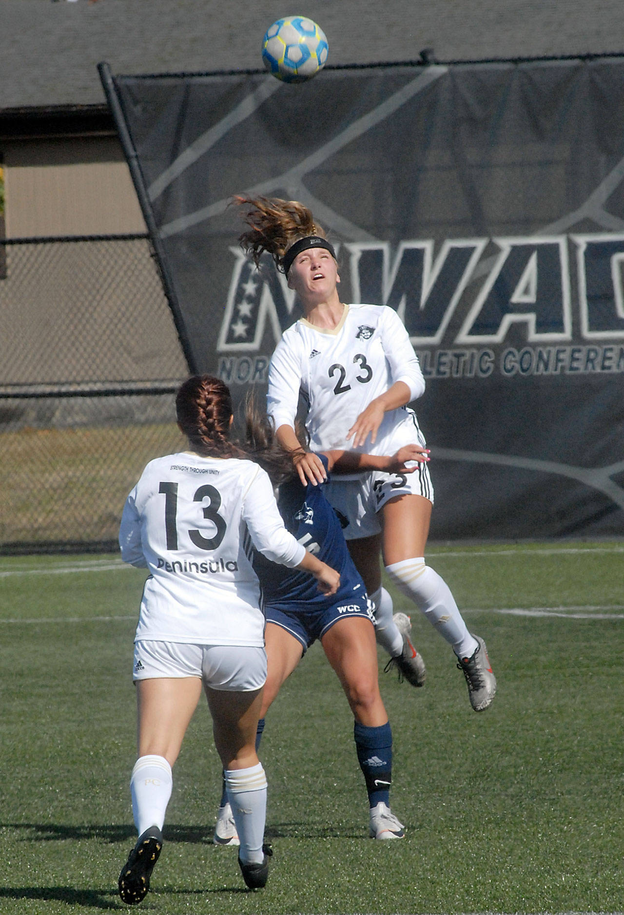 Keith Thorpe/Peninsula Daily News Peninsula’s Mackenzie Corkill goes up and over Whatcom’s Sophia Pagnotta for the header as her teammate, Grace Hipke, looks on during Wednesday’s match at Wally Sigmar Field.