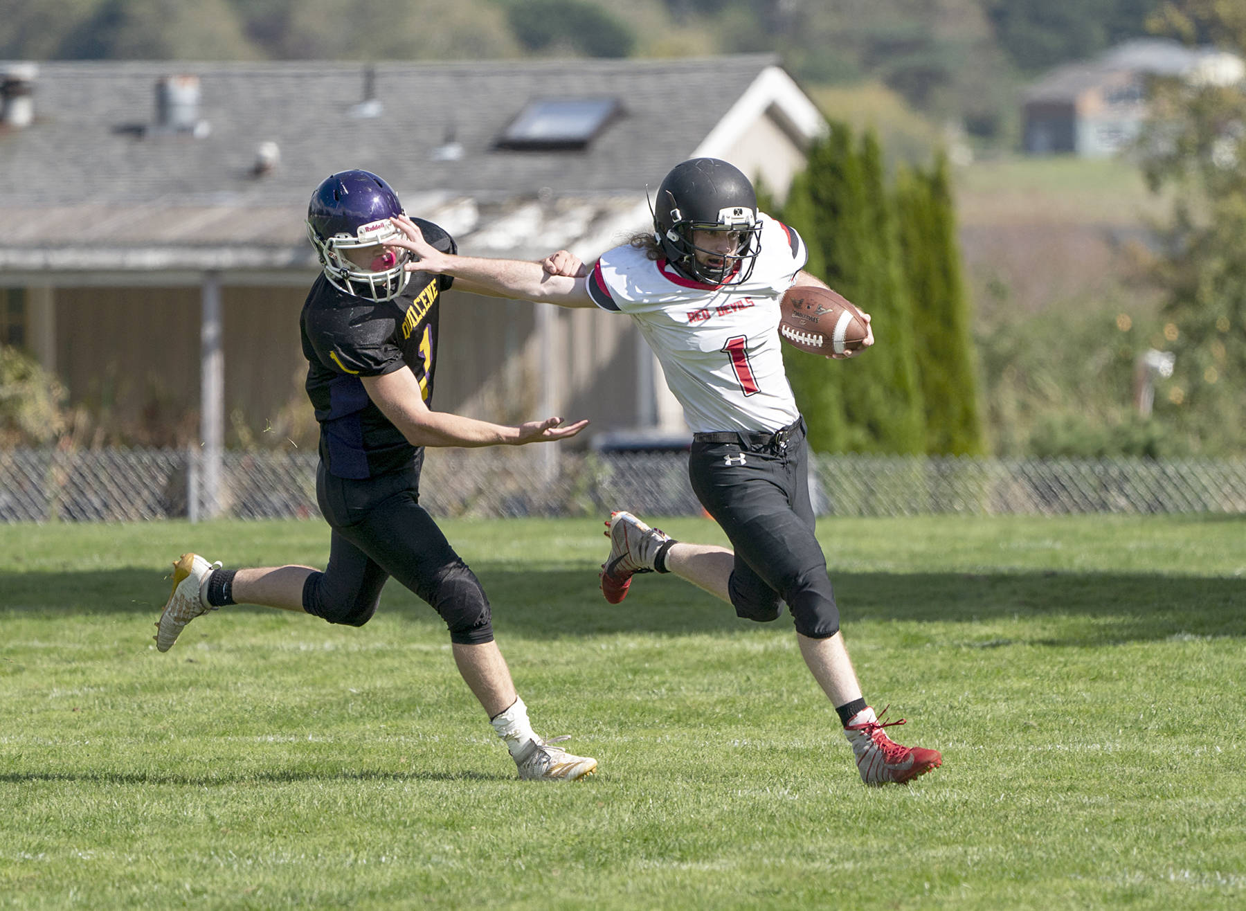 <strong>Steve Mullensky</strong>/for Peninsula Daily News                                Neah Bay’s Meric Soeneke stiff arms Quilcene’s Chase Newman during the Red Devils’ 60-39 win Saturday in Quilcene.