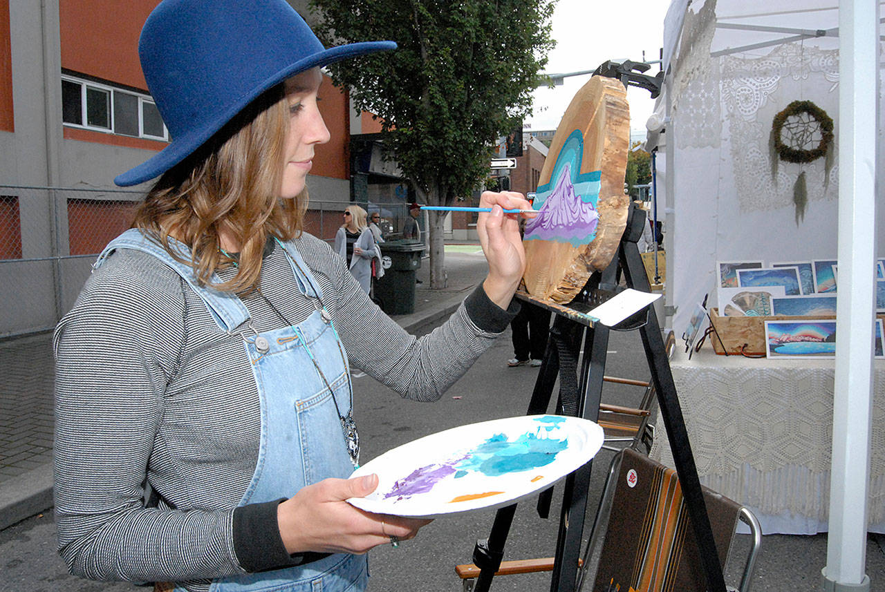 Gianna Andrews, of Vashon Island-based Gianna Andrews Art, paints a new creation at her booth at Saturday’s Arts & Draughts Festival in downtown Port Angeles. (Keith Thorpe/Peninsula Daily News)