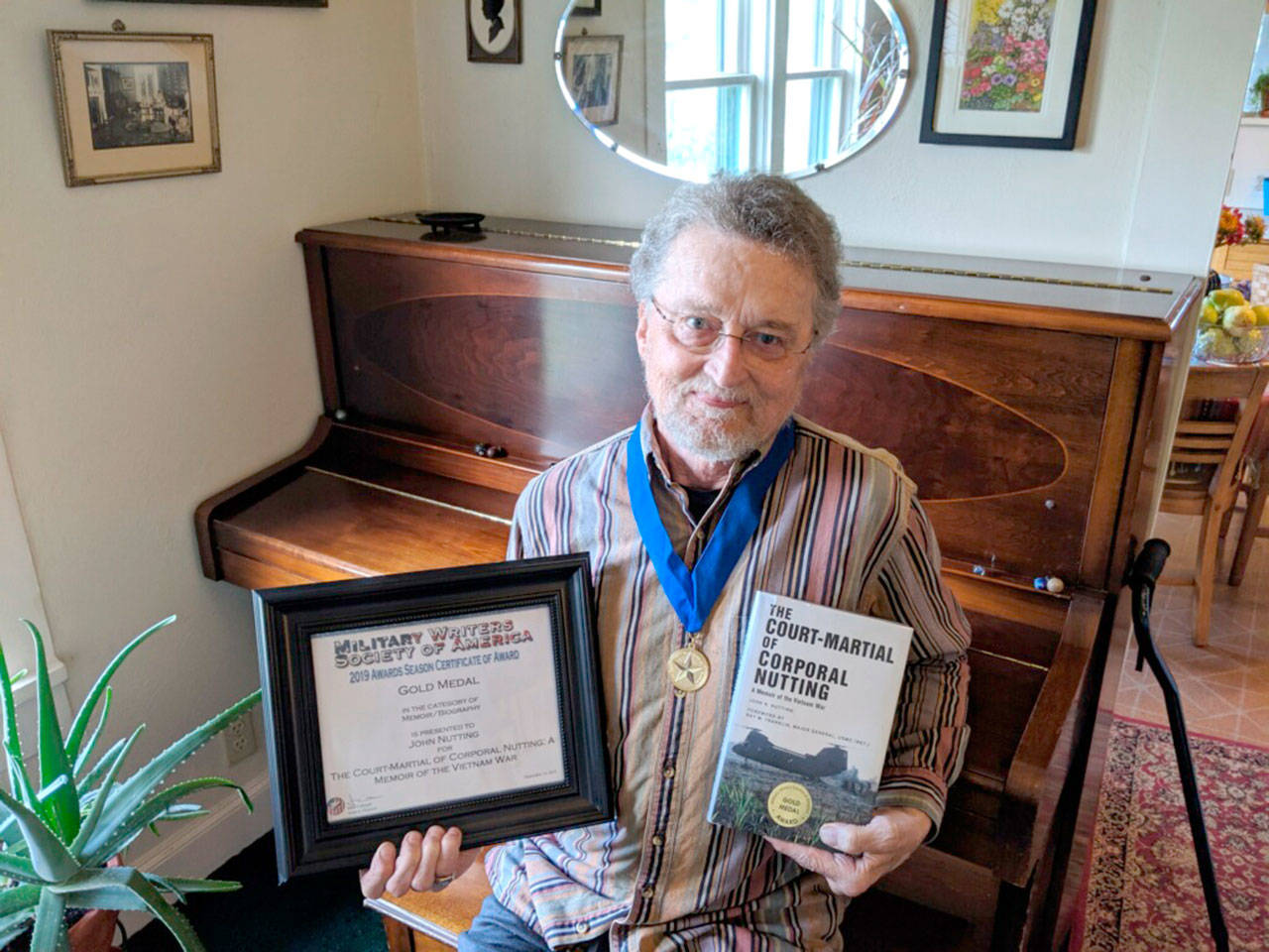 John Nutting displays his award and his memoir in his Port Angeles residence.