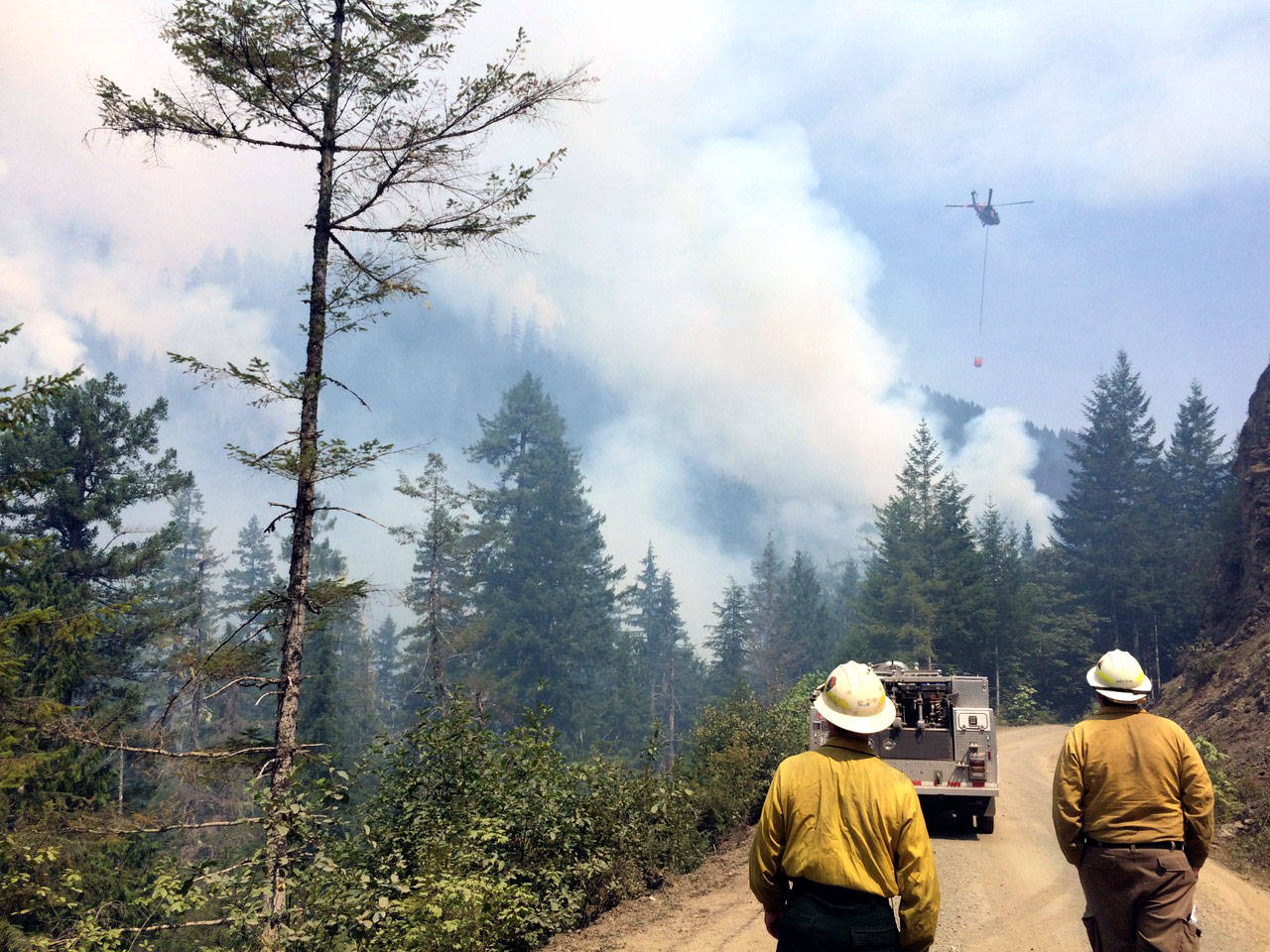 Firefighters approach the Maple Fire in Mason County in August 2018 as a helicopter in the distance drops water on the blaze. (State Department of Natural Resources)